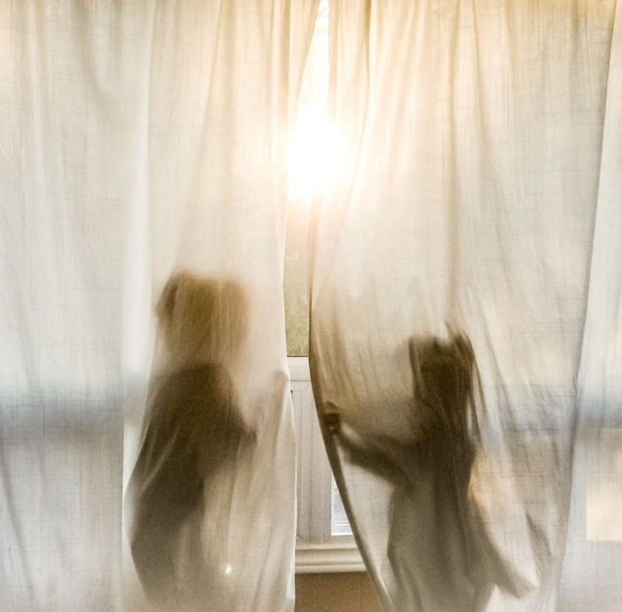Two children play behind a sheer curtain