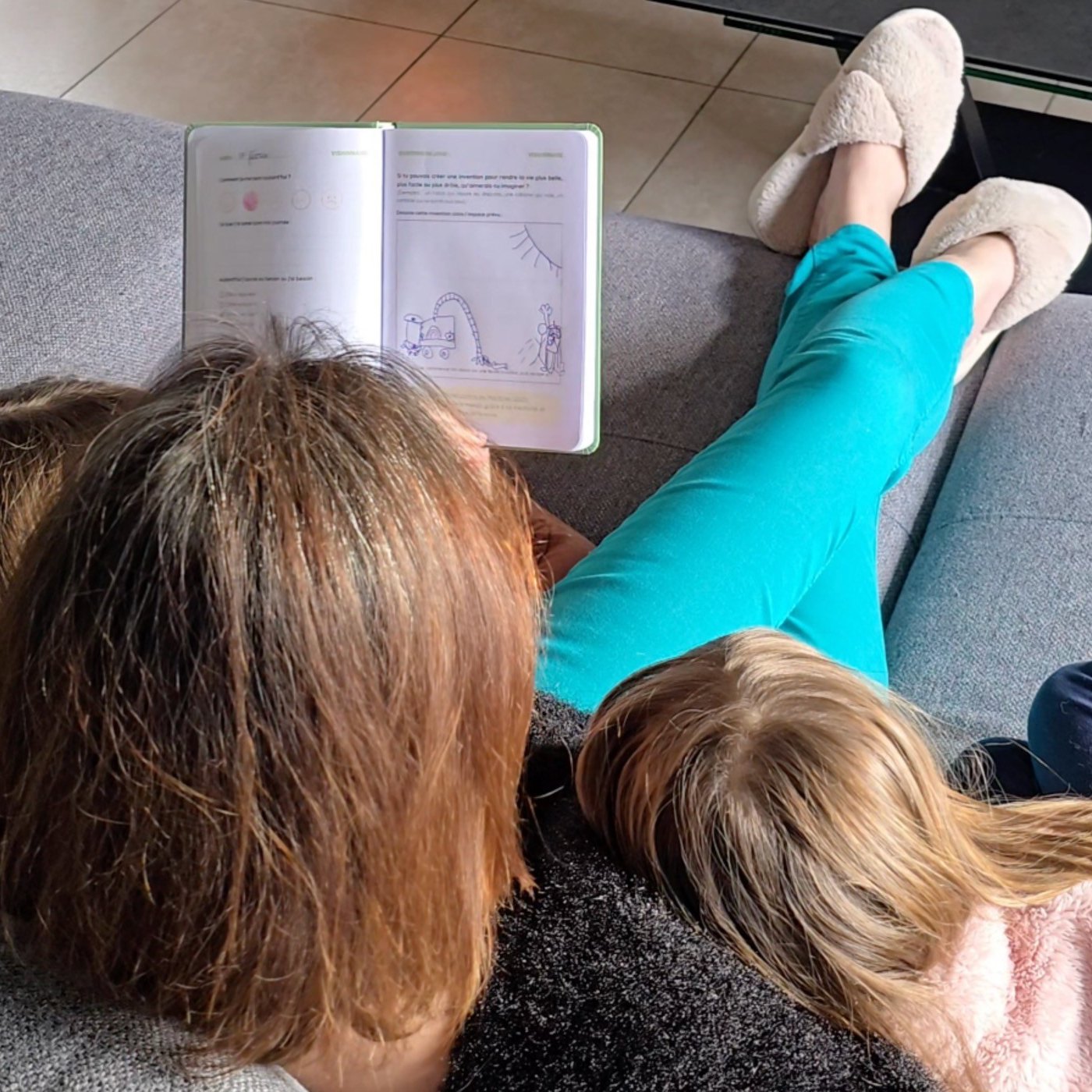 A mom and her kids read a journal page together on the couch